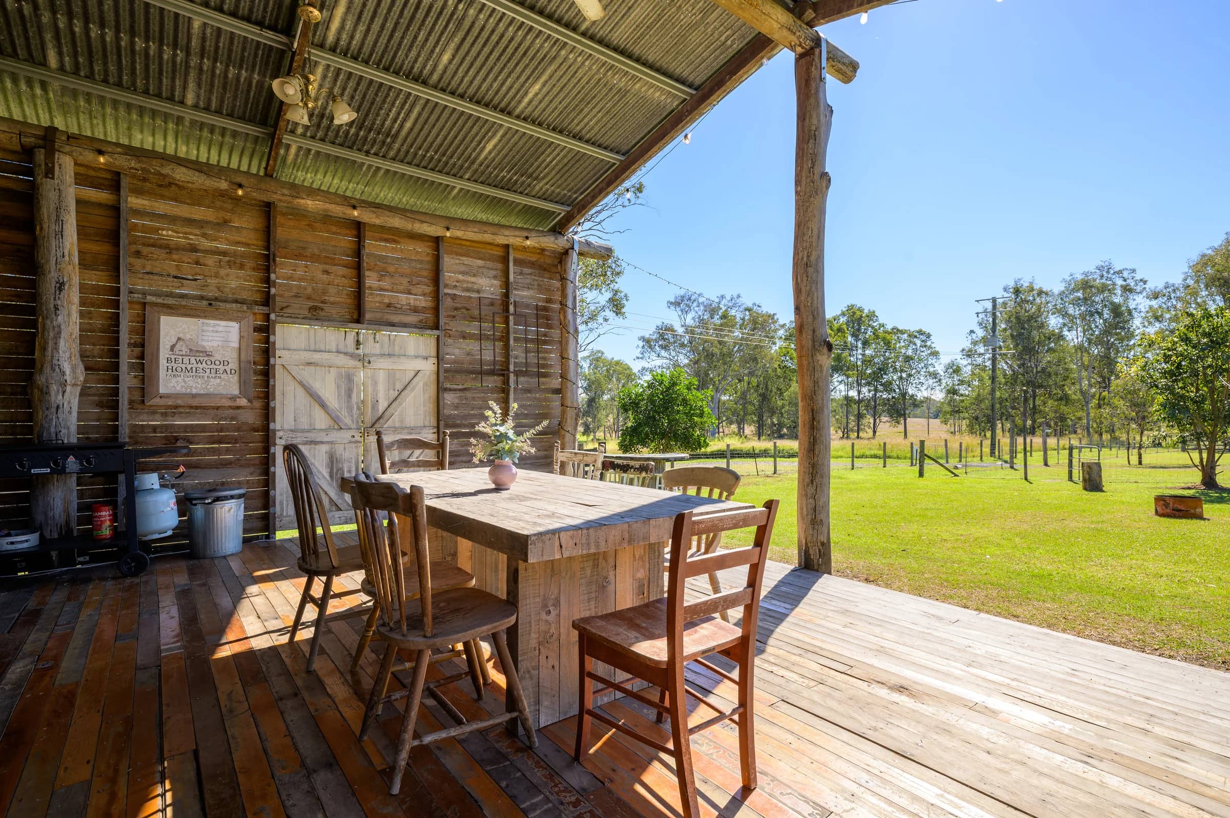 A timber table on the open side of the barn, looking out across the grassy campground