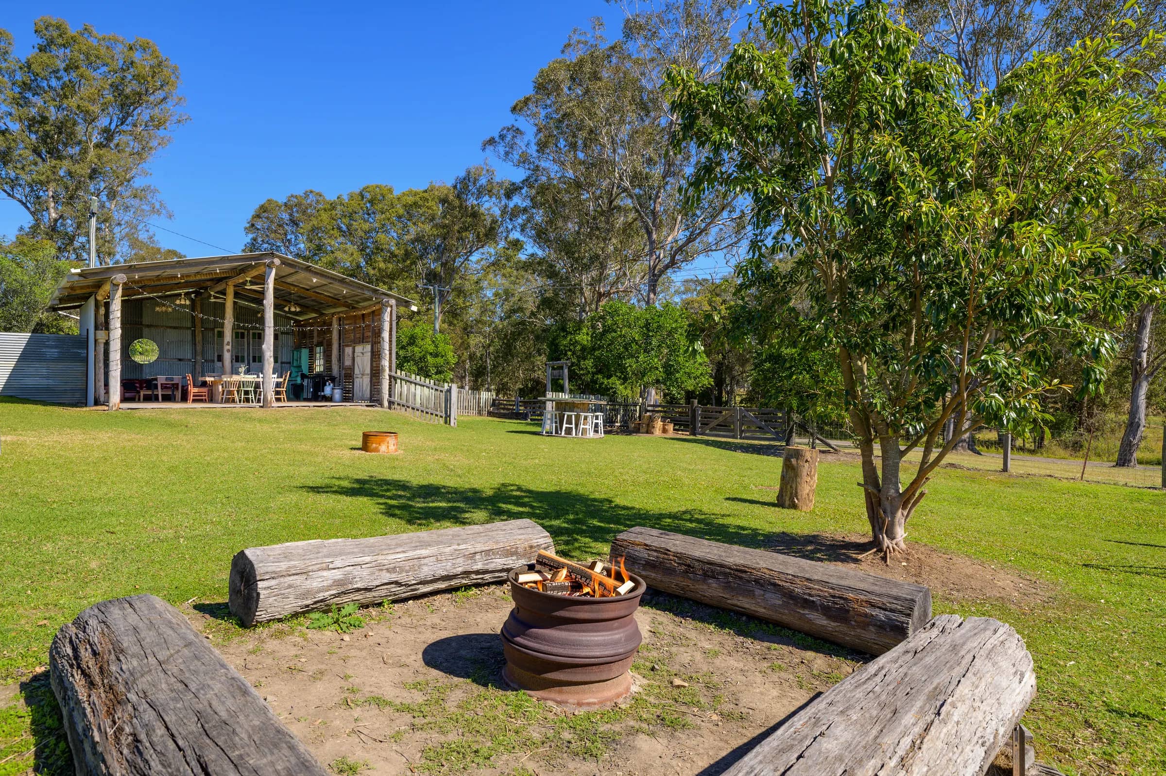 A circle of log seats around the fire pit, with Bellwood’s open barn beyond
